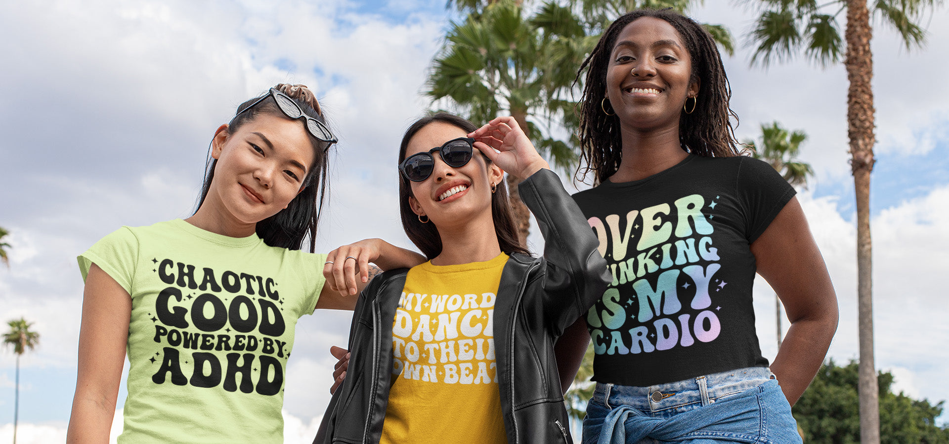 Three women wearing t-shirts with motivational phrases outdoors.